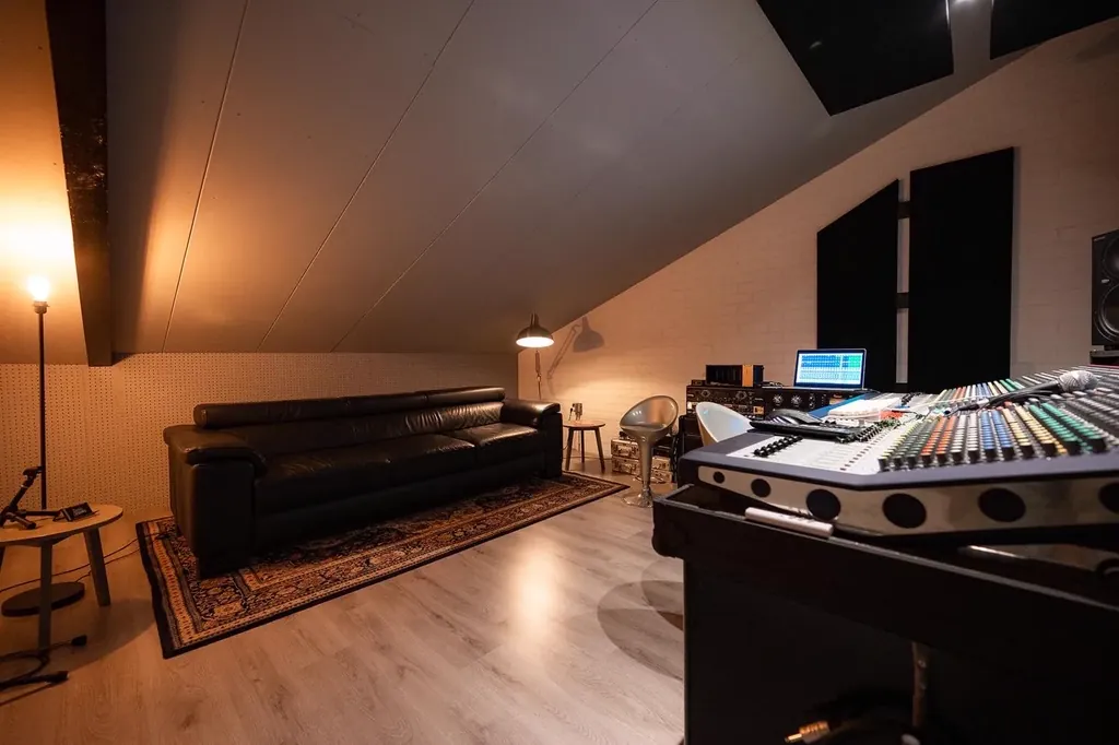 Control room lounge area at Dennis Geraads Studio with leather sofa, warm lighting and large analog mixing console