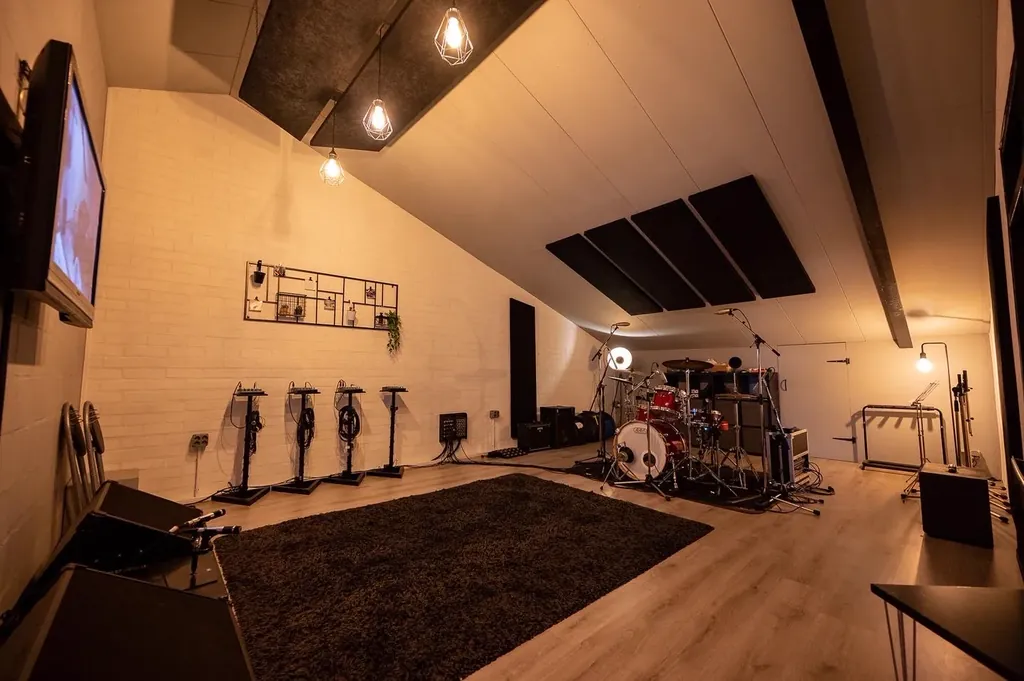 Live room at Dennis Geraads Studio with drum kit, microphone stands and acoustic ceiling panels