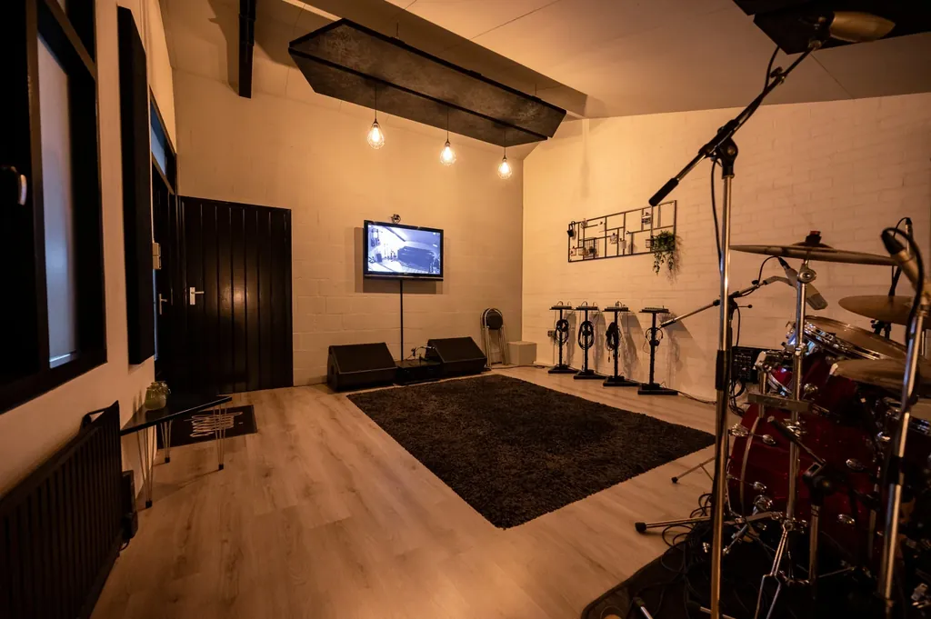 Acoustically treated recording room at Dennis Geraads Studio in Echt with drum kit, studio monitors and warm ambient lighting
